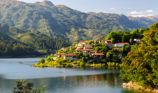 Vakantiepark met glamping-accommodaties aan een meer, omgeven door bergen en groene bossen.