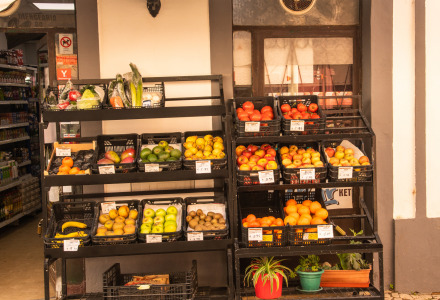 Esposizione di frutta e verdura fresca fuori da un negozio con prodotti colorati e piante in vaso.