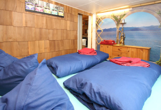 Camera da letto alla Holiday home Susanne in Germania con biancheria blu, pareti in legno e murale lago.