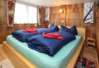 Camera da letto nella Holiday home «Susanne 58 qm» con letto matrimoniale, biancheria blu e pareti in legno in Germania.