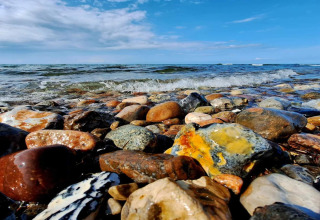 Kleurrijke keien en kleine golven aan het strand bij het 4-persoons vakantiehuis in Frederiksværk, Denemarken.