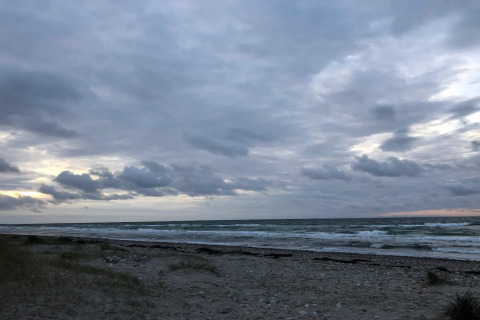 Vista de la playa y el mar en Frederiksværk, Dinamarca, desde una casa de vacaciones bajo un cielo nublado.