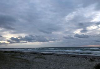 Uitzicht op het strand en de zee bij Frederiksværk in Denemarken vanuit een vakantiehuisje onder wolken.