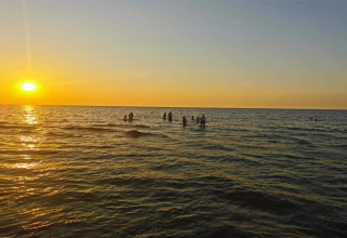Atardecer sobre el mar con personas nadando cerca de la casa de vacaciones en Frederiksværk, Dinamarca.