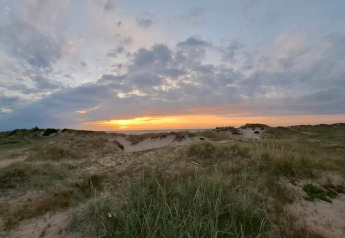 Puesta de sol sobre las dunas en Frederiksværk, Dinamarca, vista desde alojamiento vacacional.