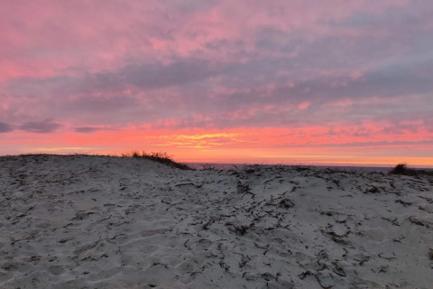 Solnedgang over sandklitter set fra feriehus i Frederiksværk, Danmark, med smukke rosa skyer.