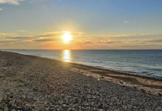 Solnedgang over stranden nær Frederiksværk, Danmark, set fra feriebolig ved kysten med sten.