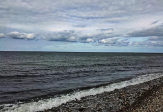 Vista sul mare calmo e il cielo nuvoloso dalla spiaggia rocciosa vicino a Frederiksværk, Danimarca.