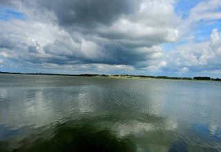 Uitzicht op een vredig meer en dramatische lucht bij het 4-persoons vakantiehuis in Frederiksværk, Denemarken.