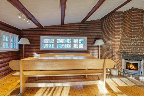 Sala de comedor rústica con chimenea, banco de madera y ventanas en Frederiksværk, Dinamarca.