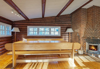 Sala da pranzo rustica con camino, panca in legno e finestre nella casa vacanze a Frederiksværk, Danimarca.