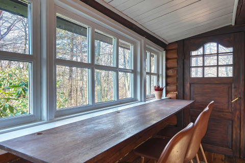 Lichte raamplek met houten bureau en stoelen in een lodge in Frederiksværk, Denemarken, uitzicht natuur.