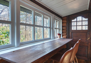 Lichte raamplek met houten bureau en stoelen in een lodge in Frederiksværk, Denemarken, uitzicht natuur.