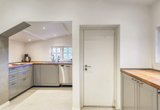 Moderne keuken in vakantiehuis in Frederiksværk, Denemarken met grijze kasten en houten werkblad.