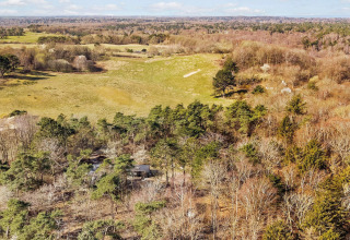 Luftfoto af landskab ved feriehus til 4 personer i Frederiksværk, Danmark, omgivet af skov og åbne marker.