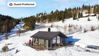 Met sneeuw bedekte chalet in Passebekk met gasten buiten, omgeven door bos, met Guest Preferred label.