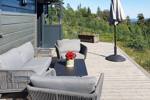 Terrazza esterna di uno chalet in Svezia con arredi da giardino grigi, ombrellone e vista naturale.