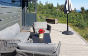 Terrazza esterna di uno chalet in Svezia con arredi da giardino grigi, ombrellone e vista naturale.