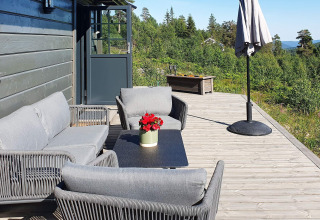 Terrazza esterna di uno chalet in Svezia con arredi da giardino grigi, ombrellone e vista naturale.
