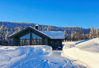 Chalet de vacances pour six personnes à Passebekk, Suède, entouré de neige et forêts enneigées, ciel bleu.