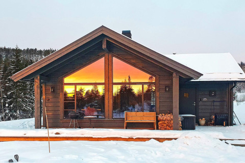 6-persoons chalet in Passebekk, Zweden, sneeuw en zonsondergang prachtig weerspiegeld in ramen.