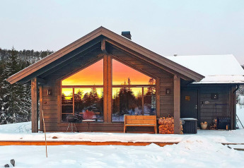 6-persoons chalet in Passebekk, Zweden, sneeuw en zonsondergang prachtig weerspiegeld in ramen.