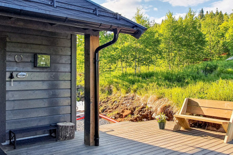 Terrazza in legno del chalet per 6 persone a Passebekk, Svezia, con panchina e vista sulla foresta verde.