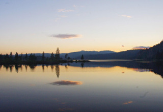 Sunset over a calm lake and tree reflections, viewed from a 6 person holiday home in Passebekk, Sweden.