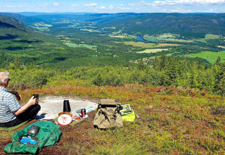 Älterer Mann hat Picknick auf einem Hügel mit weitem Talblick bei '6 person holiday home in Passebekk', Schweden.
