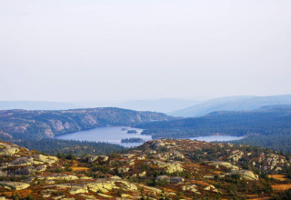 Vista da uno chalet a Passebekk, Svezia, con lago placido, foreste e colline rocciose sullo sfondo.