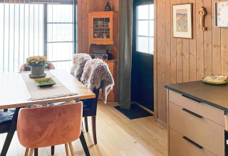 Gemütlicher Essbereich in einer holzverkleideten Ferienhütte mit moderner Küche und natürlichem Licht.