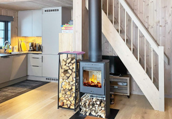 Interno di casa vacanze con stufa a legna, cucina moderna e scala a Passebekk, Svezia.