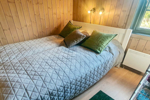 Et hyggeligt soveværelse i en 6-personers chalet i Passebekk, Sverige, med træpaneler og dobbeltseng.