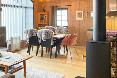 Hyggelig stue i Passebekk chalet med spisebord, pelsbetrukne stole, pejs og store vinduer i Sverige.