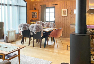 Hyggelig stue i Passebekk chalet med spisebord, pelsbetrukne stole, pejs og store vinduer i Sverige.