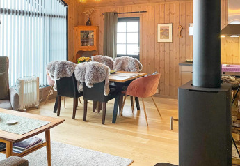 Acogedor salón en chalet de Passebekk, Suecia, con mesa de comedor, sillas con piel y chimenea de leña.