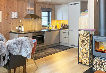 Moderne keuken en zithoek in chalet met haard, houtopslag en bontstoelen, zes persoons huis Passebekk, Zweden.
