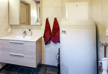 Bagno con lavabo, armadietto a specchio, due asciugamani rossi e caldaia in uno chalet a Passebekk, Svezia.