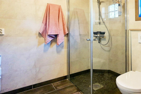 Bagno moderno con doccia in vetro, wc e asciugamano rosa in una casa vacanze a Passebekk, Svezia.