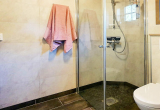 Modern bathroom with glass shower, wall-mounted toilet and pink towel in a holiday home in Passebekk, Sweden.