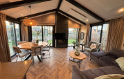 Interior view of Hackfort lodge showing modern living area, dining table, and large windows to the garden.