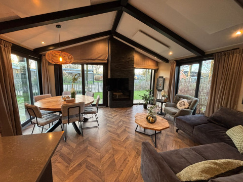 Intérieur du lodge Hackfort avec salon moderne, table à manger et grandes fenêtres donnant sur le jardin.