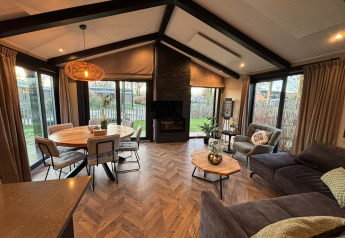 Intérieur du lodge Hackfort avec salon moderne, table à manger et grandes fenêtres donnant sur le jardin.