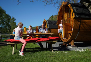 Familia disfruta al aire libre frente a cabañas de barril en Camping Rissbach - Wijnvaten Renania-Palatinado glamping.
