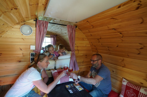 Famille partageant un moment convivial dans une cabane en bois au Camping Rissbach - Wijnvaten Rhineland-Palatinate.