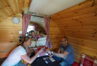 Gezin geniet samen in een houten glampingaccommodatie bij Camping Rissbach - Wijnvaten Rijnland-Palts.