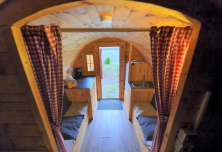 Knusse glamping-accommodatie met houten inrichting en gordijnen op Camping Rissbach - Wijnvaten Rijnland-Palts.