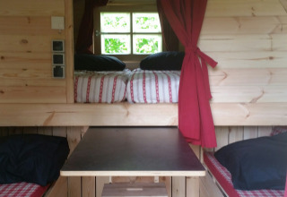 Gemütliches Holzinterieur einer Glamping-Unterkunft bei Parkcamping de Graafschap mit Sitz- und Schlafbereich.