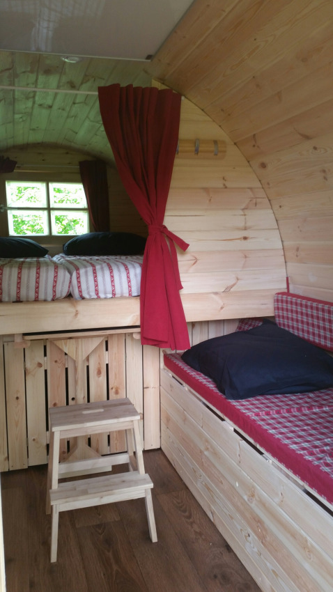 Alloggio glamping in legno con letti a castello e tende rosse al Parkcamping de Graafschap.