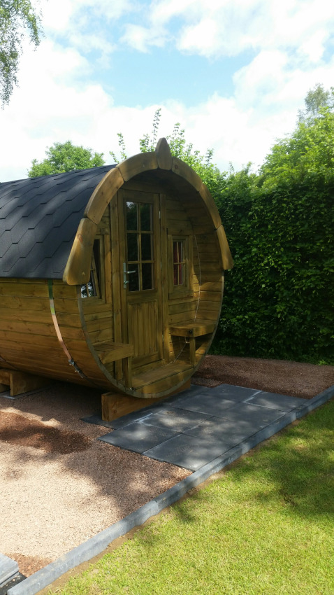 Barrel-shaped wooden glamping pod at Parkcamping de Graafschap, Gelderland, surrounded by lush greenery.